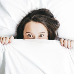 woman covering face with blanket