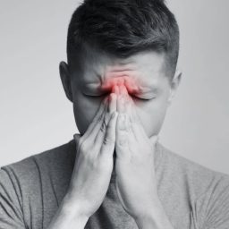 Man with sinus pressure holding his face.