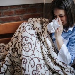 Woman experiencing sinus pressure while sitting on couch.