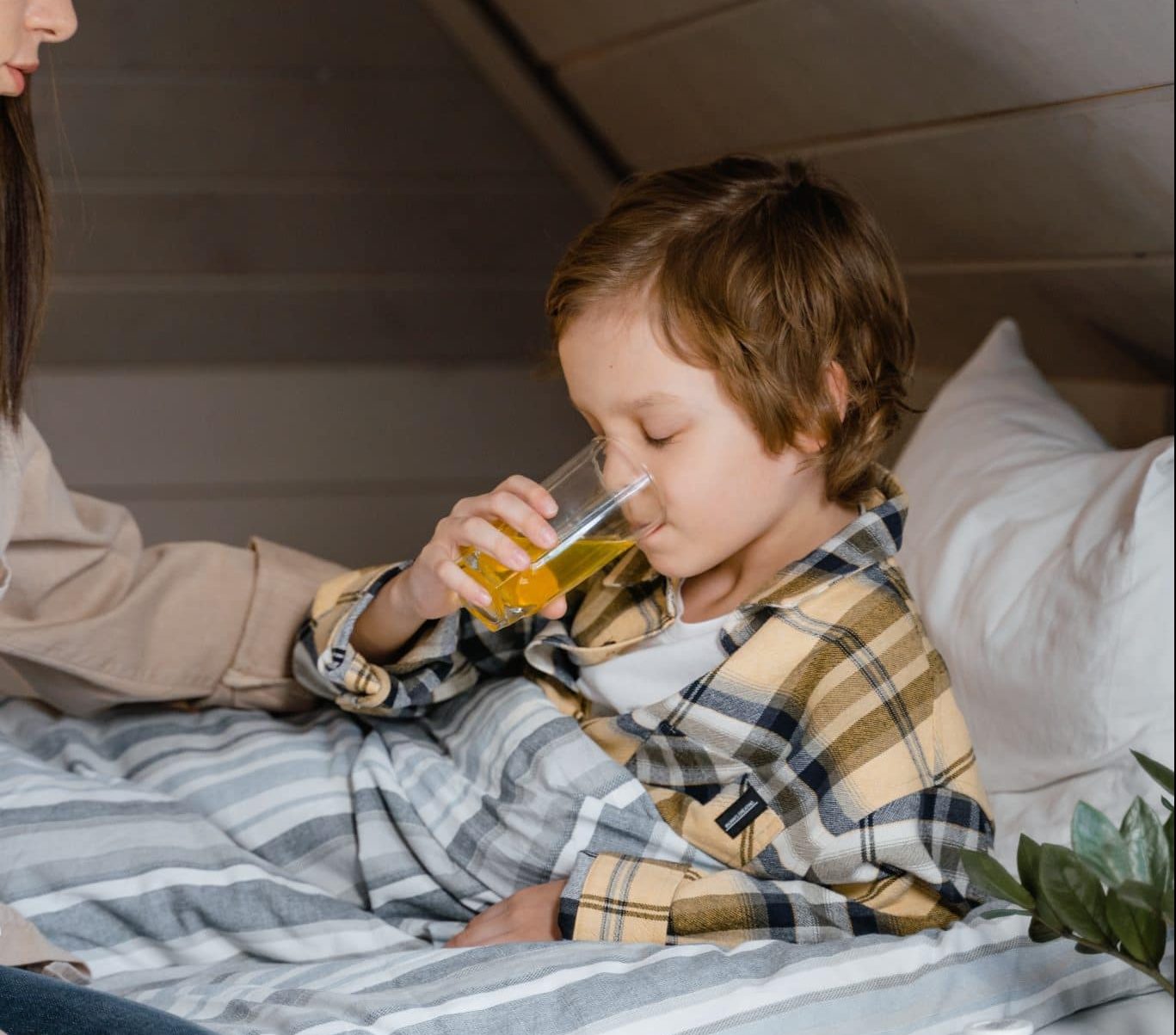 Mother giving her young son juice to help him feel better.