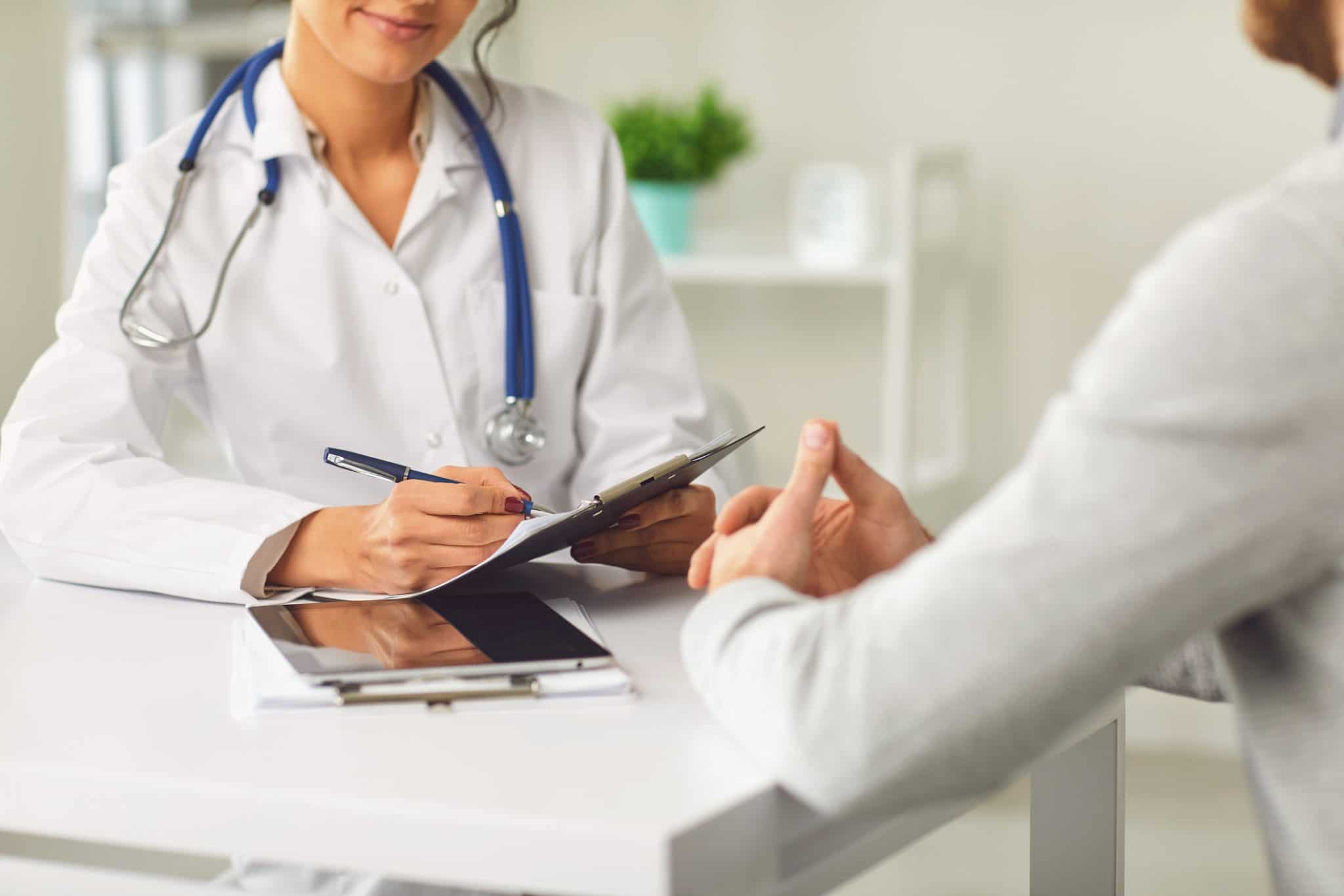 A doctor speaks with a patient inside of a medical office setting.