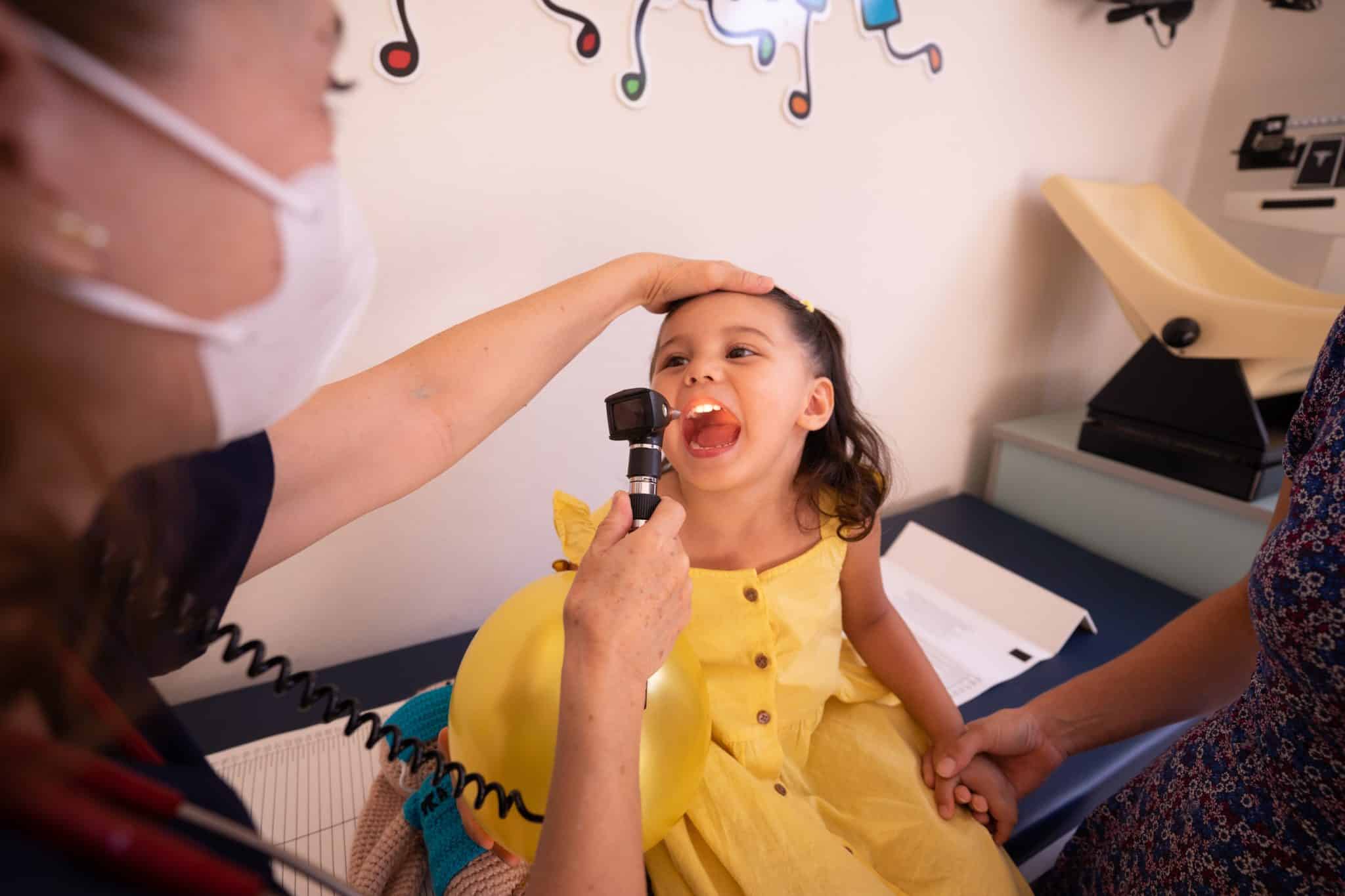 An ENT doctor examining a young girl's throat.