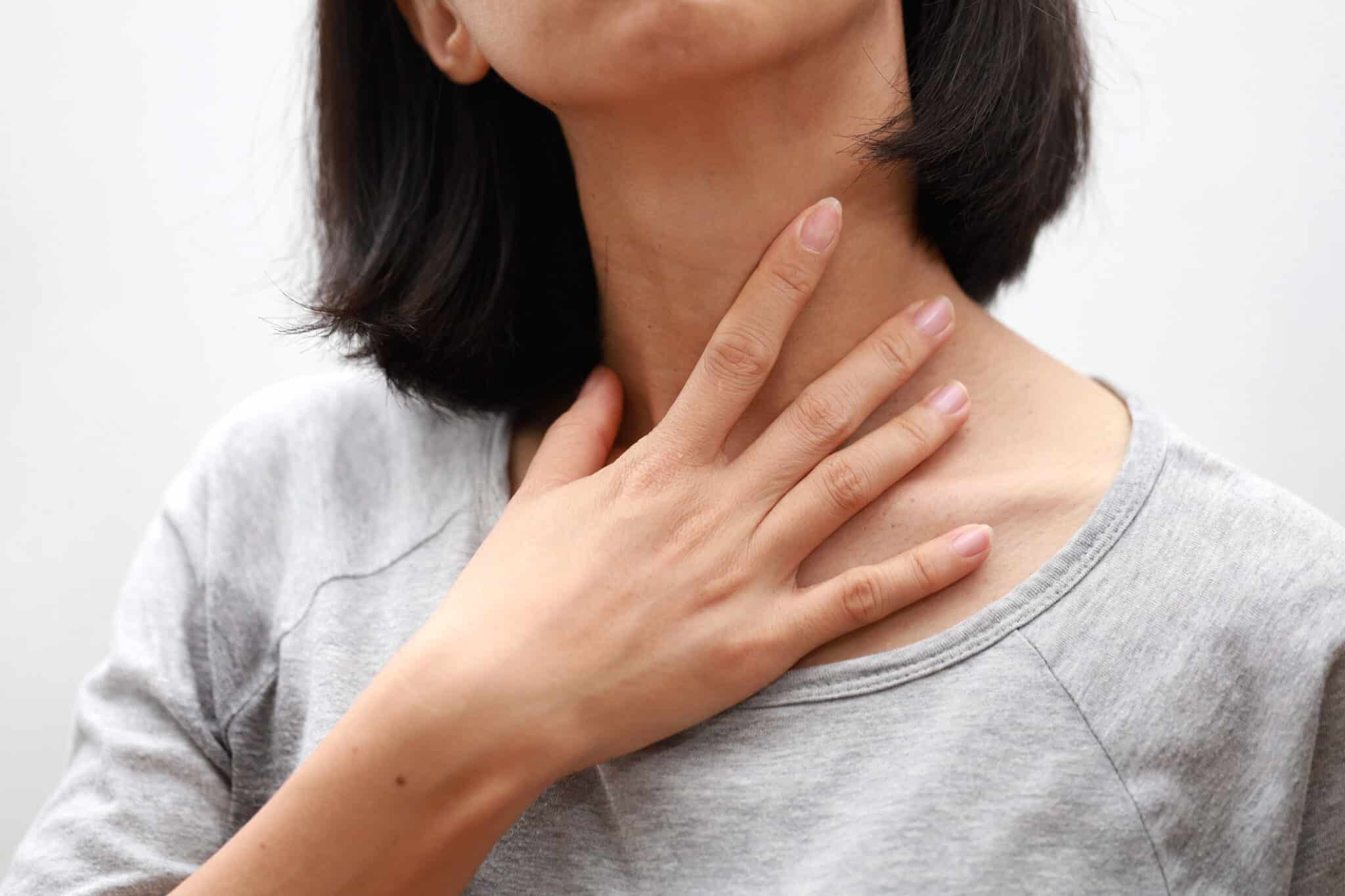 Closeup of woman hand touching her ill neck.