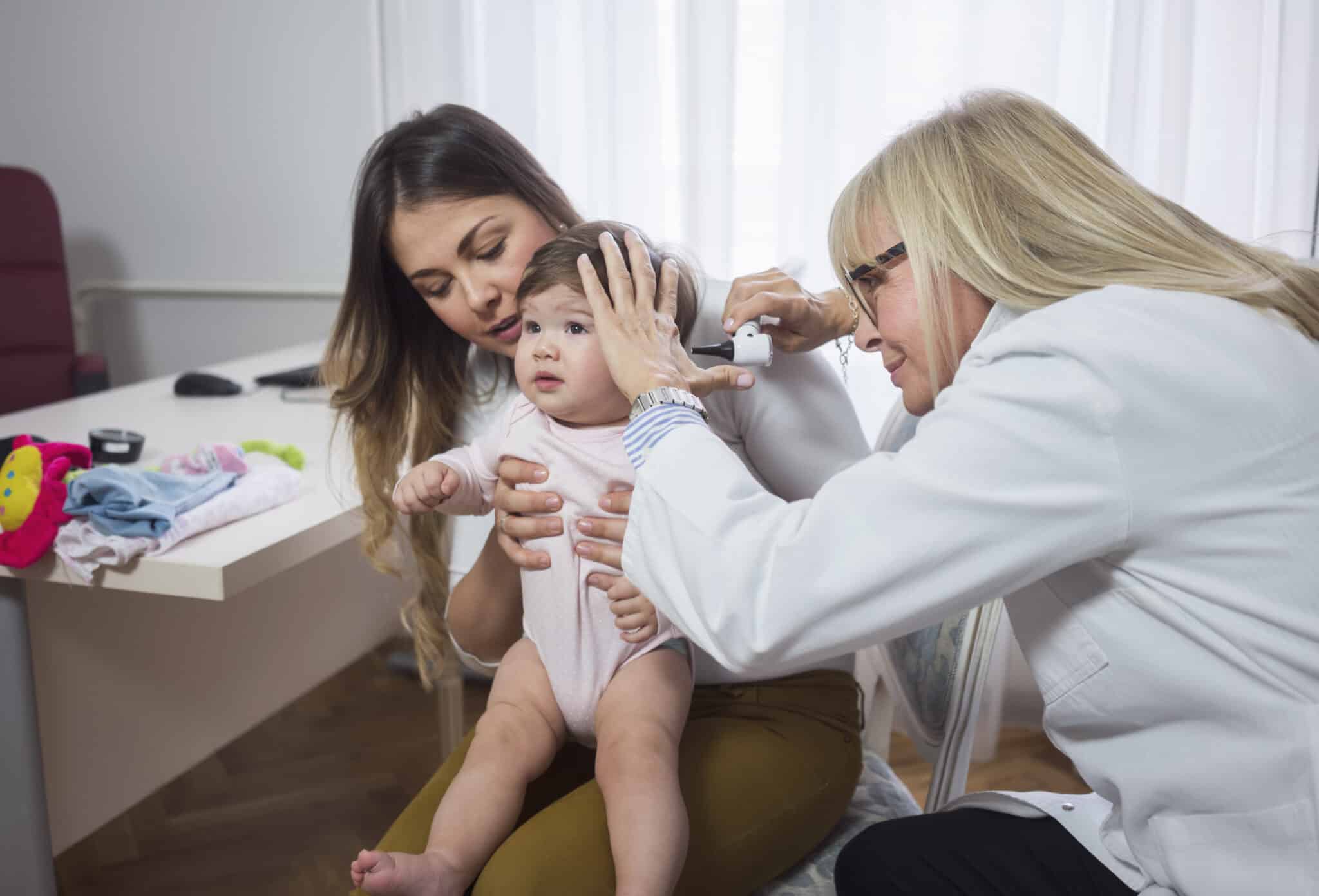 Doctor examining baby girl with Otoscope