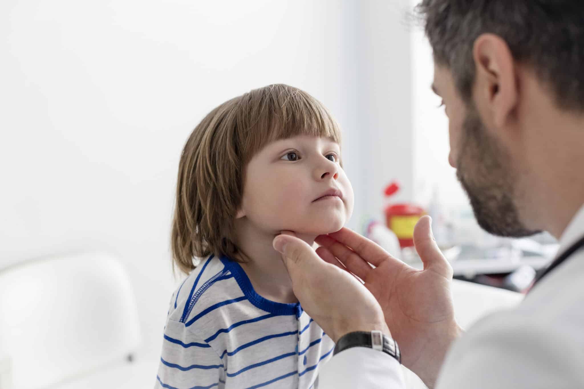 Doctor checking tonsils of patient at hospital