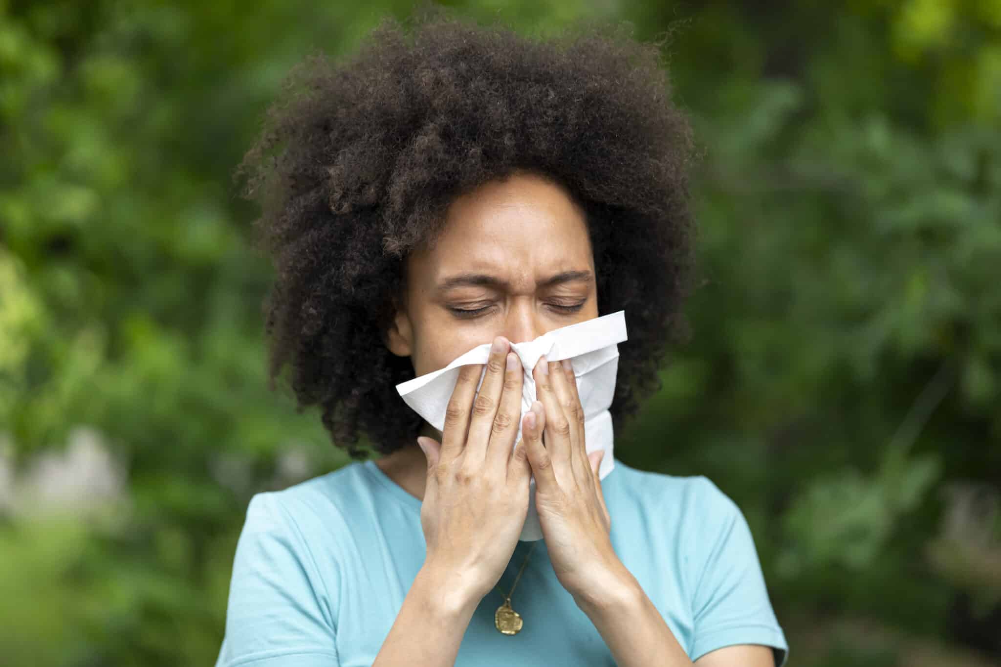 Woman with Sinusitis Problems is Feeling Displeased and Blowing Nose in Napkin During a Walk in City Park During a Summer Day.