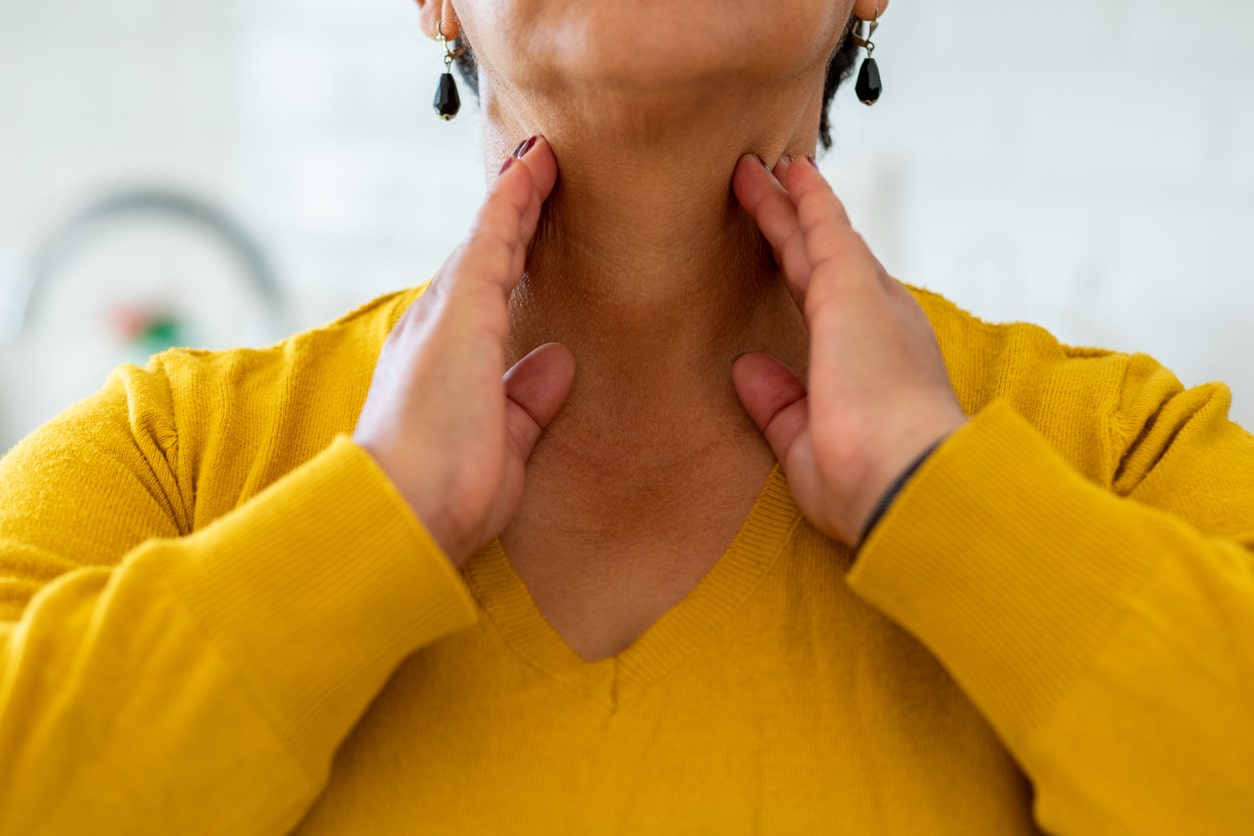 Woman with tonsillitis feeling her throat.