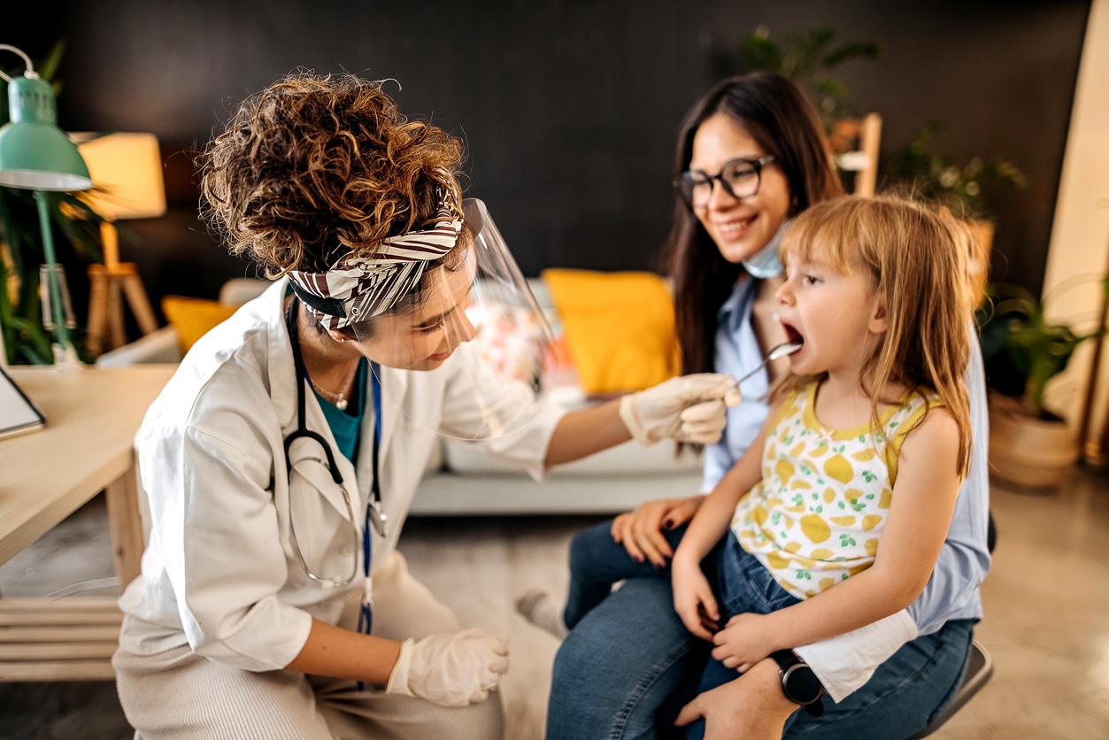 Young girl at the doctor with her mom getting her tonsils checked.