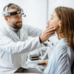 Doctor examining a young woman's nose