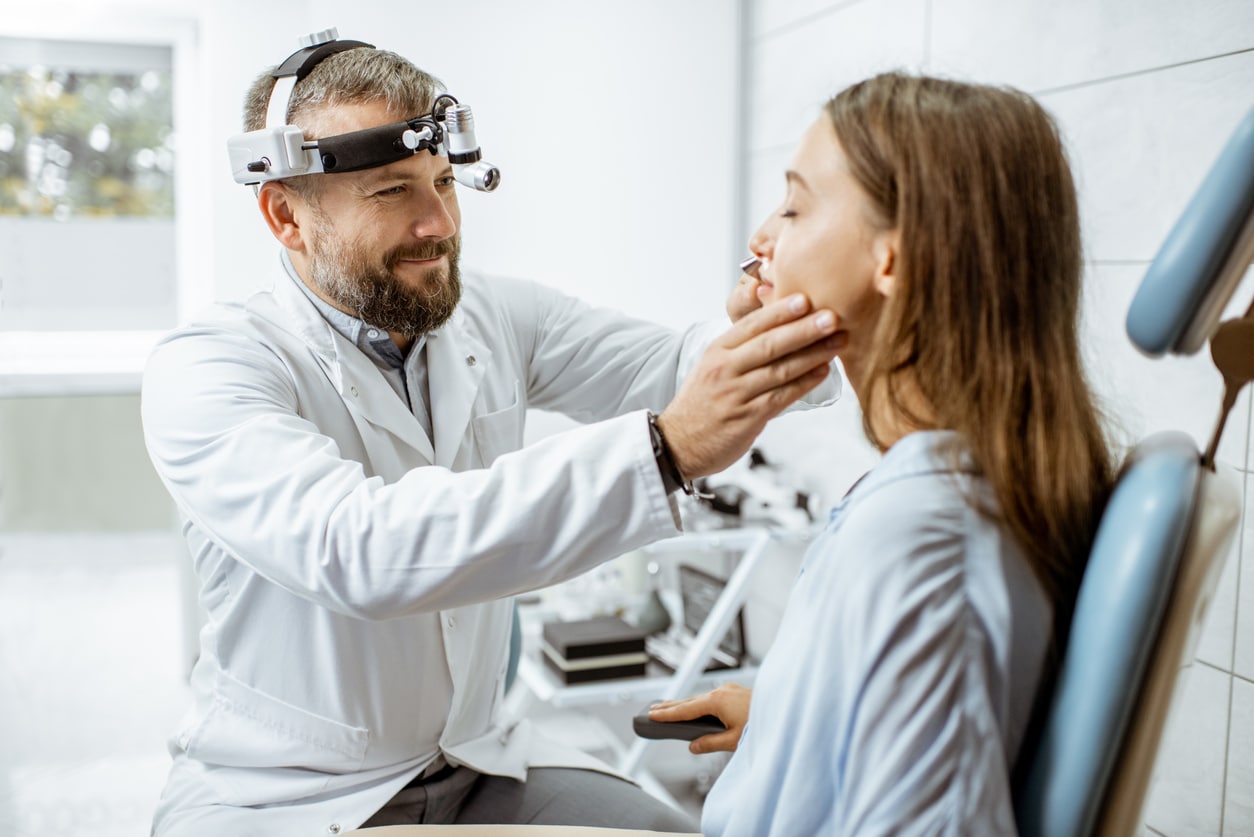 Doctor examining a young woman's nose.