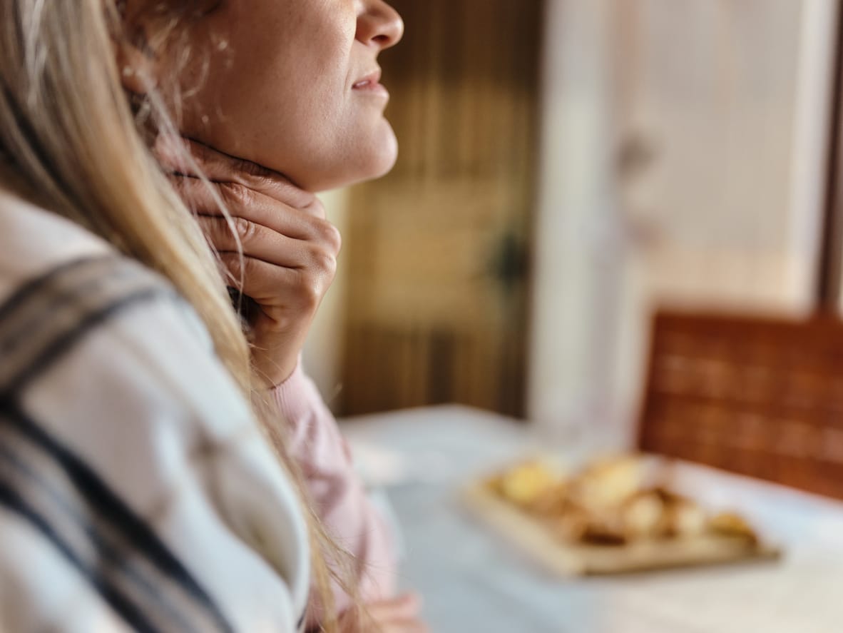 Woman with sore throat holds neck