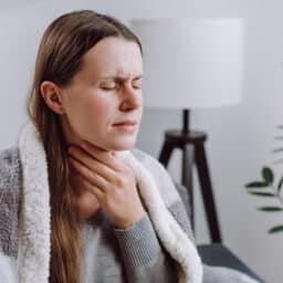 Frowning woman holding her sore throat