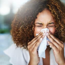 Woman with sinus infection blows nose