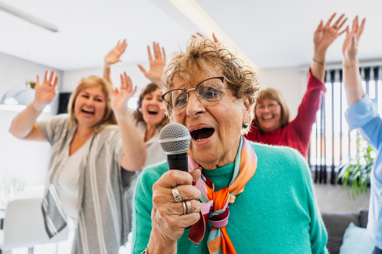 Senior woman singing karaoke with her friends.