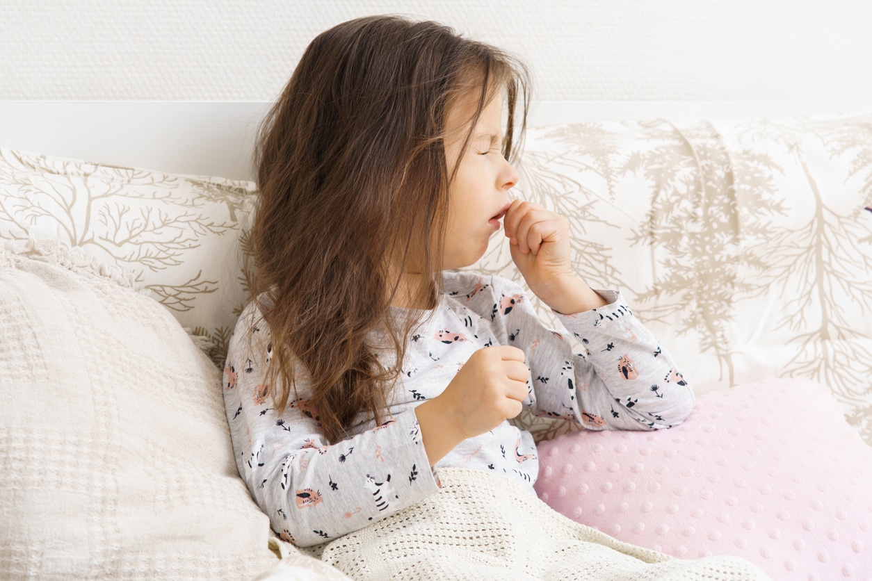 Child with allergies coughing in bed. 